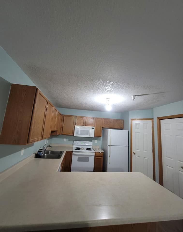 A kitchen with a refrigerator , stove , microwave and sink.