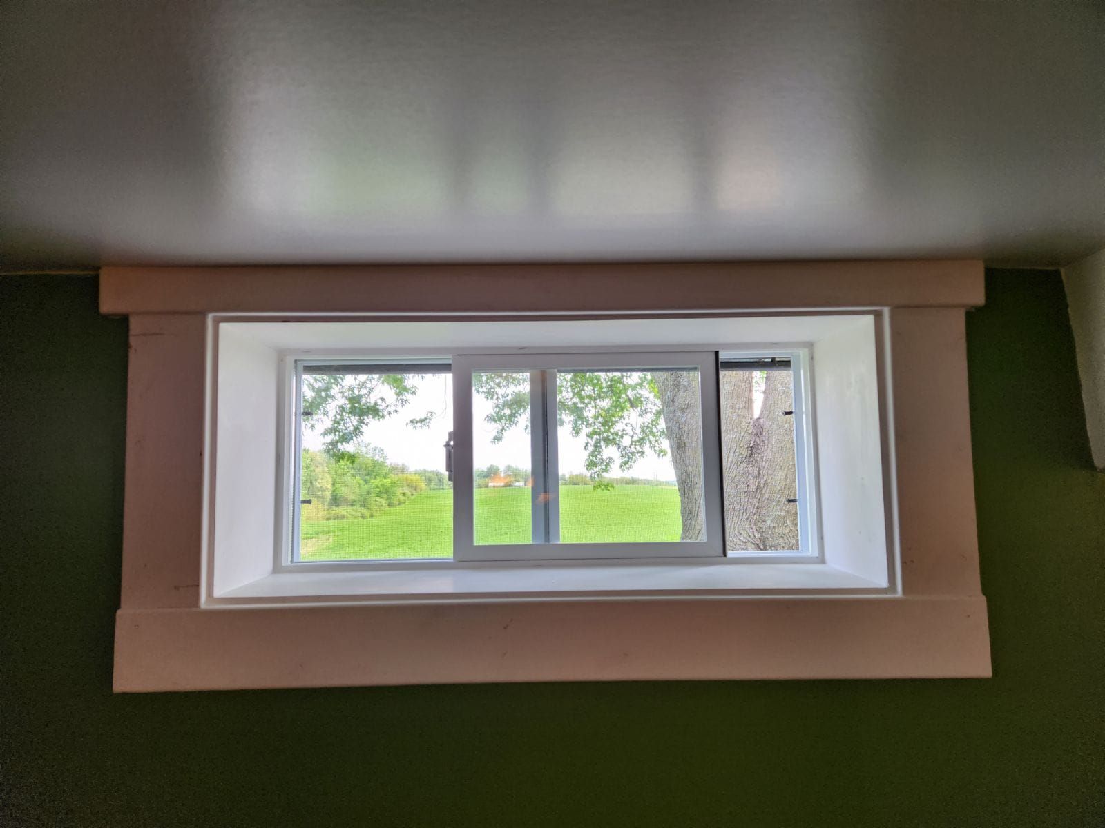 A window in a room with a view of a field and trees.