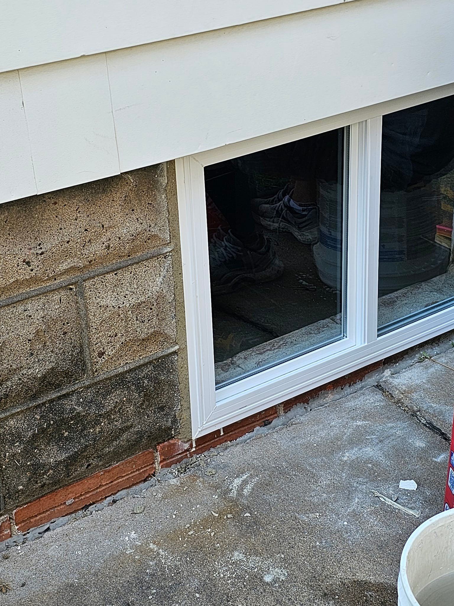 There is a window in the basement of a house.