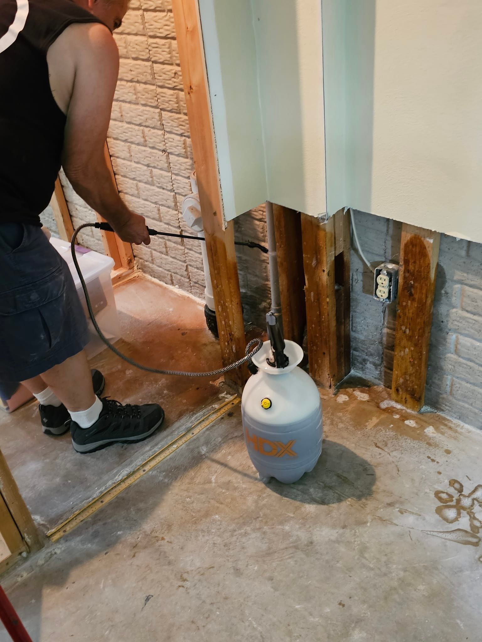 A man is spraying a propane tank with a hose.