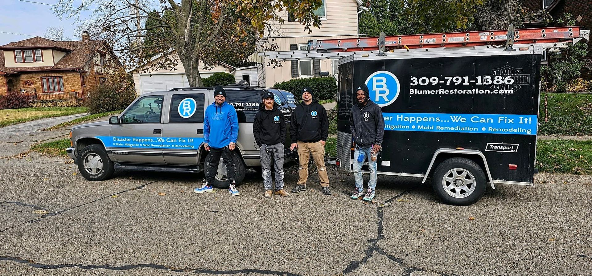 A group of men are standing in front of a truck and trailer.