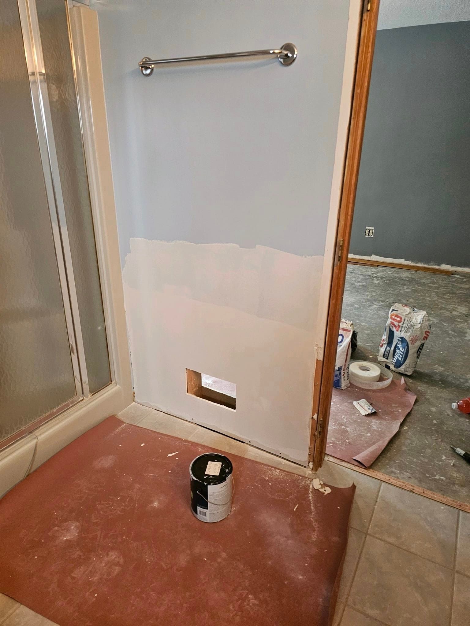 A bathroom is being painted with a bucket of paint on the floor.