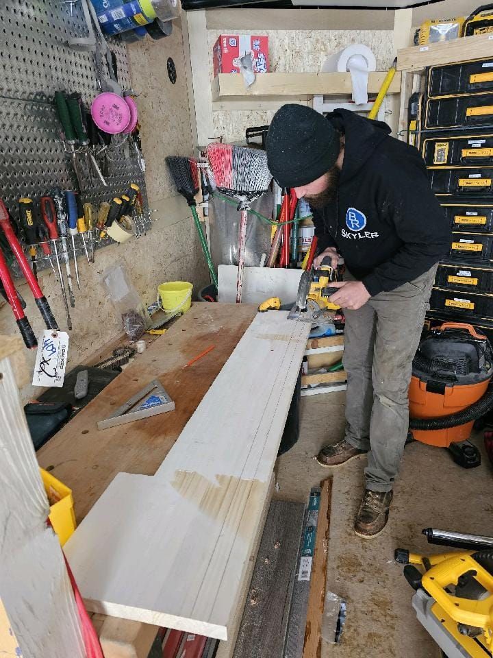 A man is working on a piece of wood in a garage.