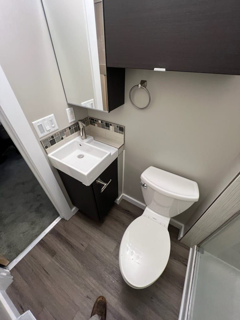 A bathroom with a toilet , sink and mirror.