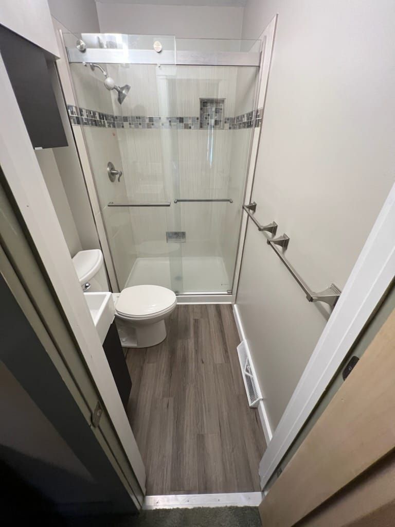 A bathroom with a toilet , sink and shower.