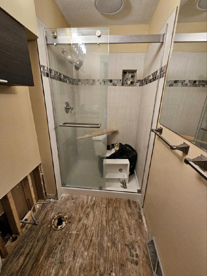A bathroom with a sliding glass shower door and a toilet.