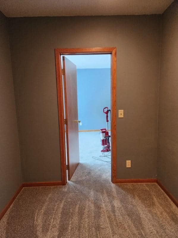 An empty room with a door open and a vacuum cleaner in it.