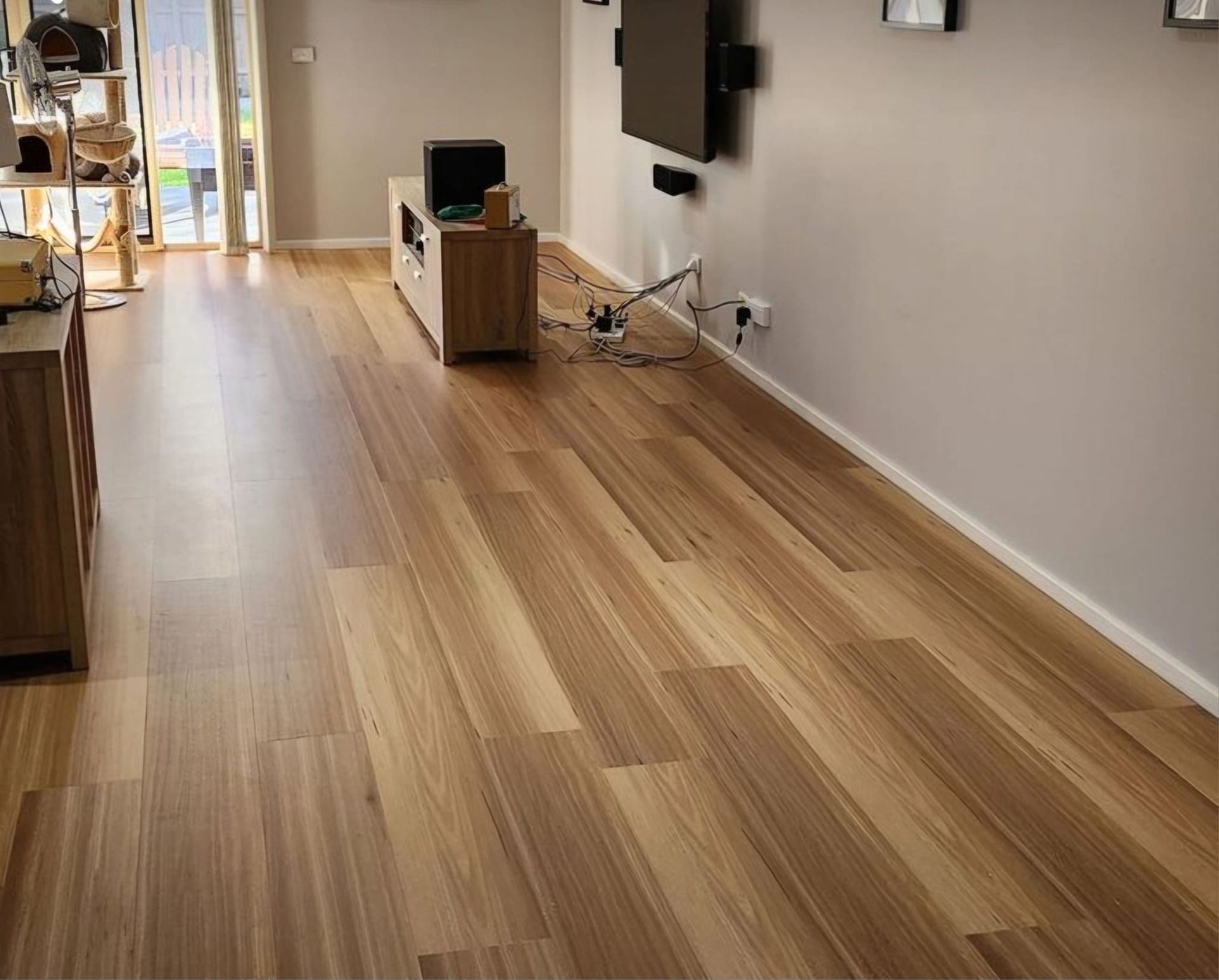 A living room with hardwood floors and a flat screen tv on the wall.