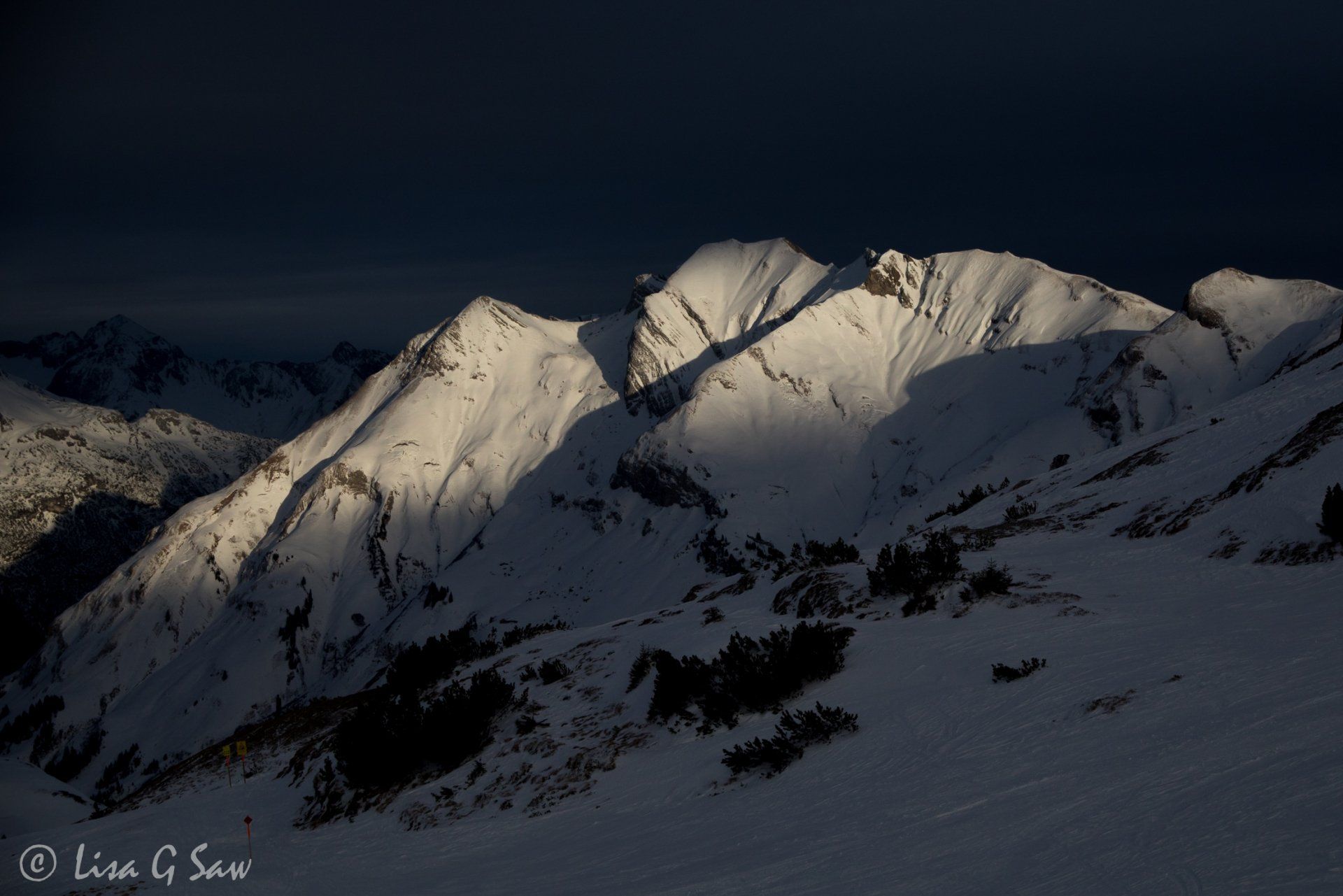 Sun shining on snow capped mountain peaks