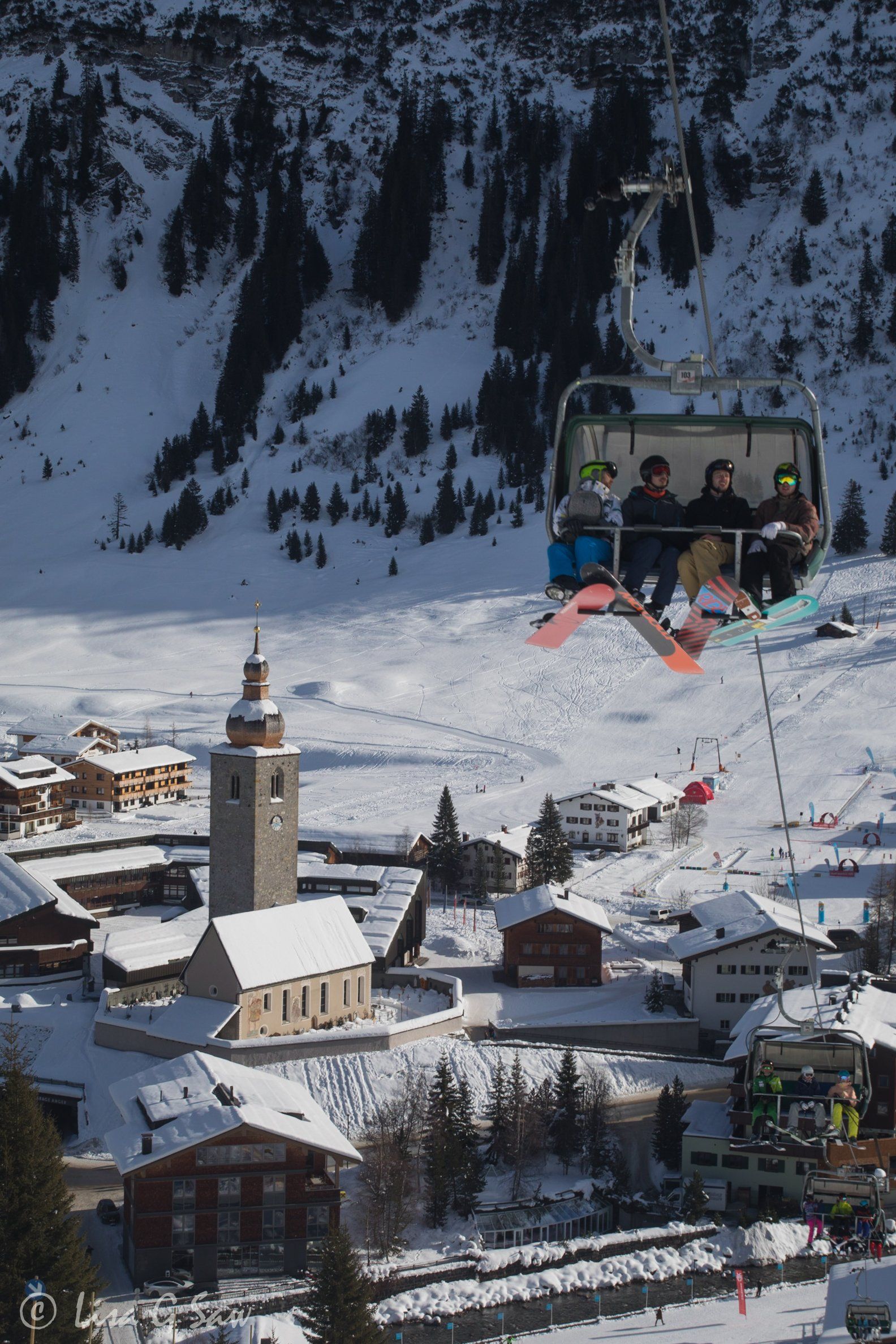 Snowboards sitting on chairlift with Lech below