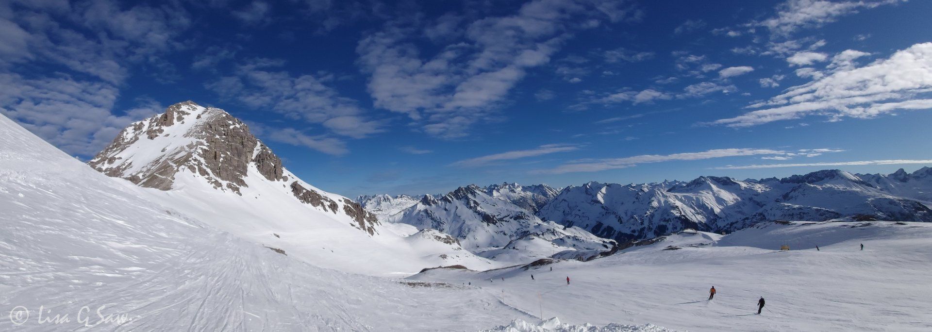 Skiers on piste and snow capped mountains