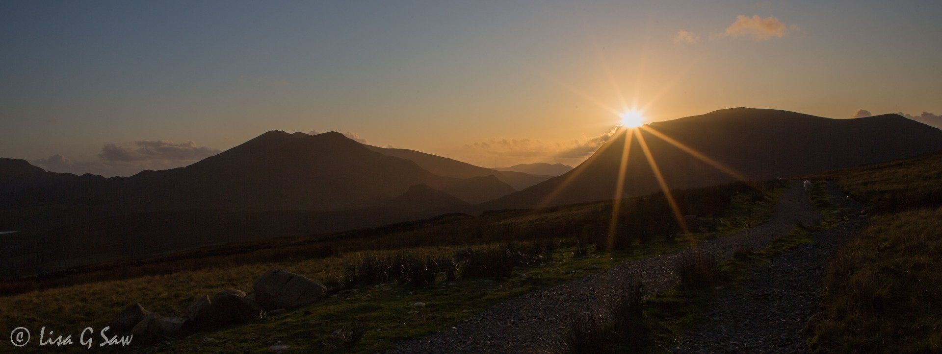 Sheep on Snowdon Ranger Path and sunburst behind mountain in Snowdonia National Park