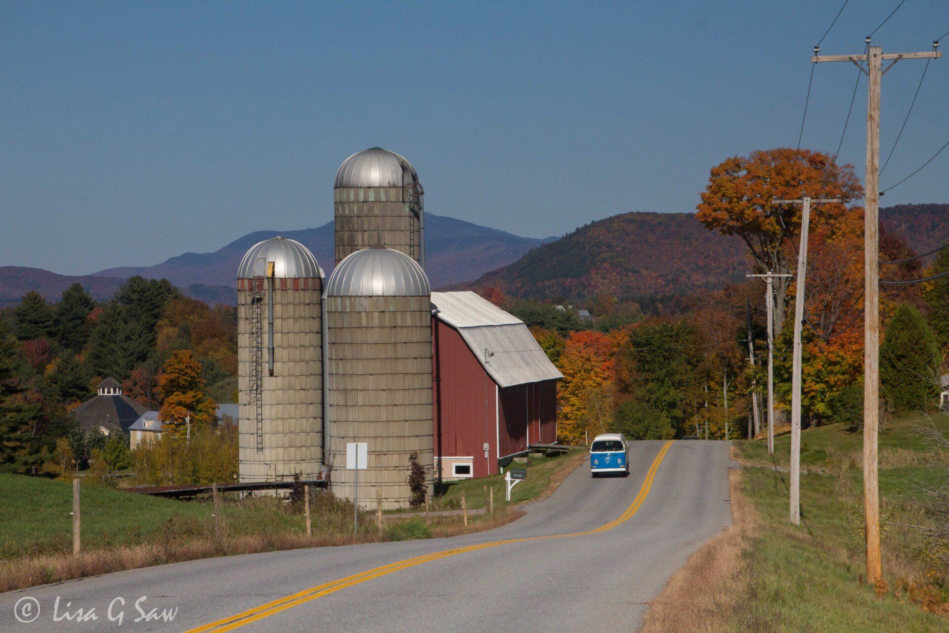 Blue VW combivan driving past farm silos
