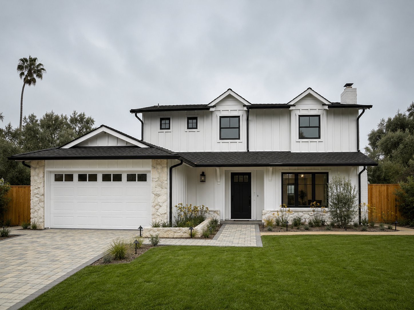 Two-story white house with attached garage, front lawn, and paved driveway under a cloudy sky.