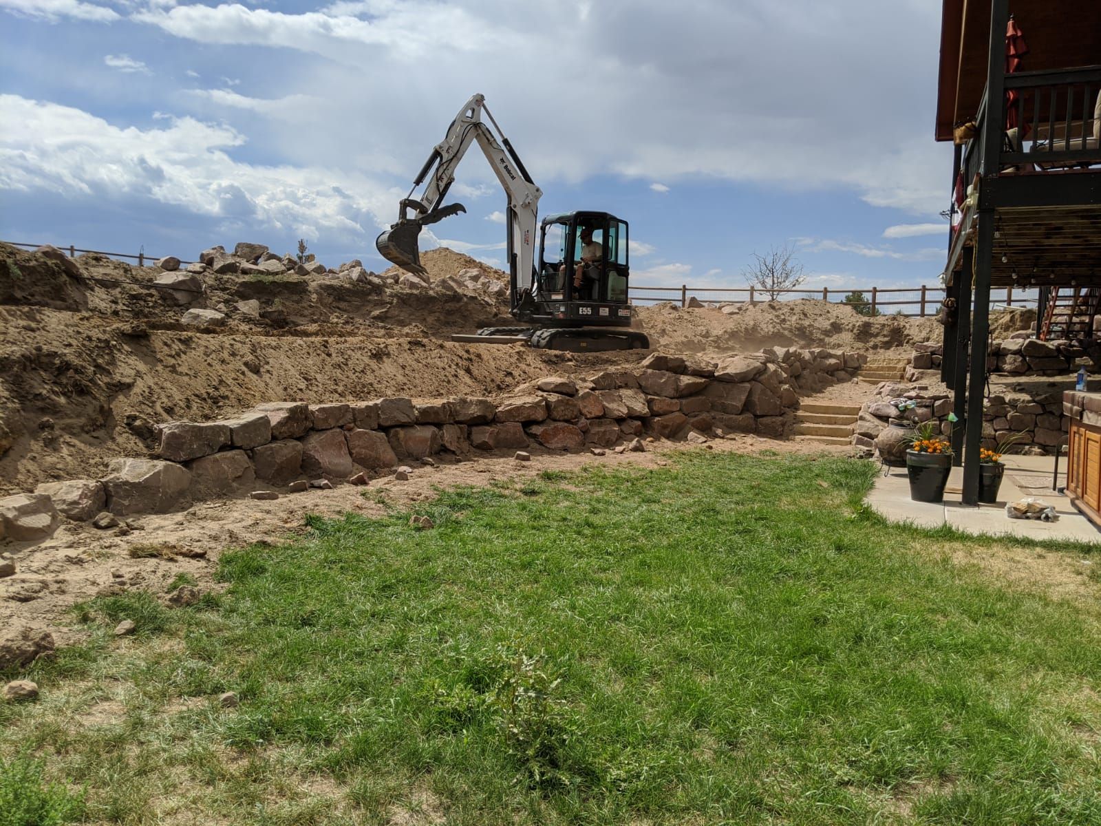 A bulldozer is digging a hole in the ground in front of a house