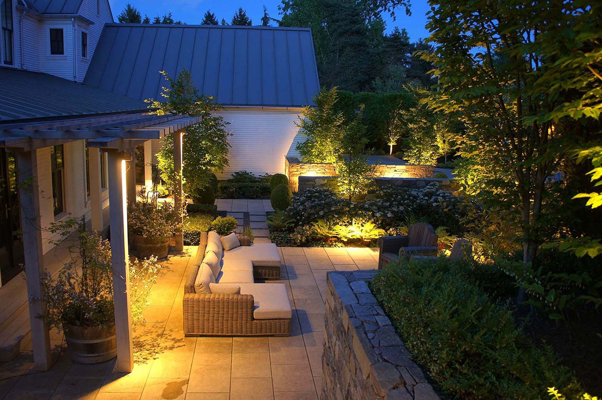 A patio is lit up at night with a pergola