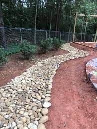 A path made of rocks in a backyard next to a chain link fence.
