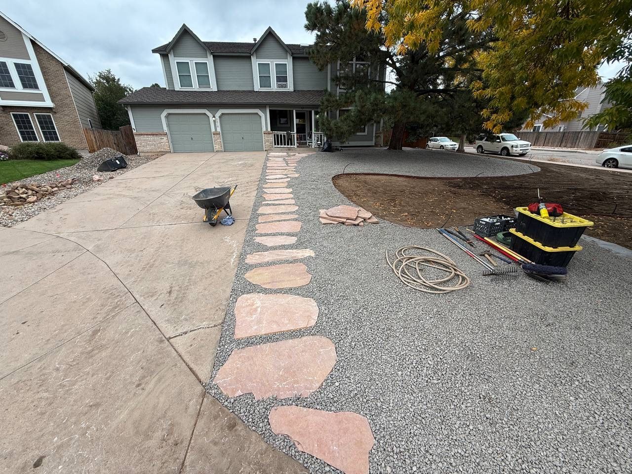 Front yard with a driveway, stone walkway, gravel landscaping, and a two-car garage under cloudy skies