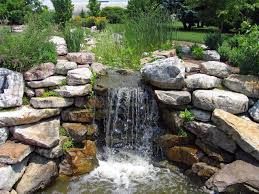 A small waterfall is surrounded by rocks in a garden.