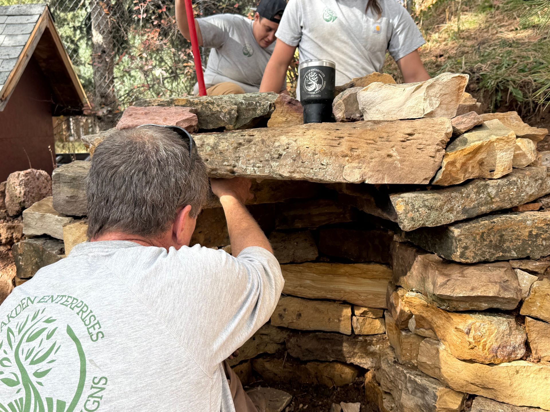Two people stacking stones to build a rustic outdoor fire pit