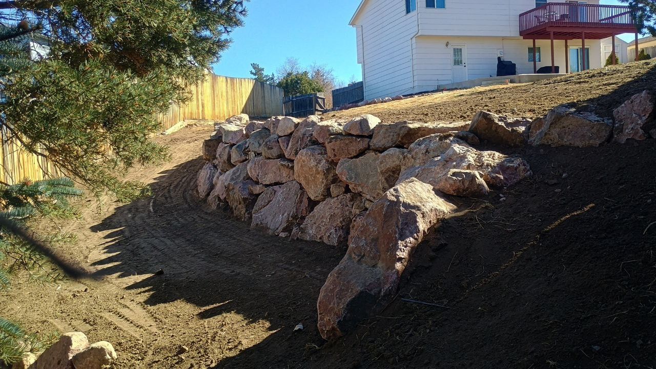 A large pile of rocks sits in front of a house