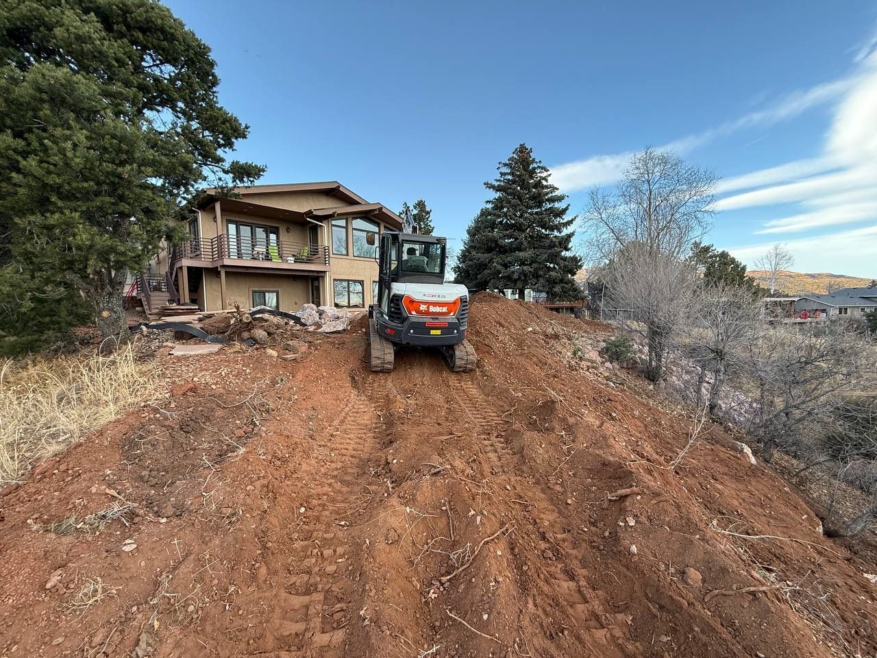 Orange ATV on a dirt driveway beside a house, with trees and a blue sky in the background