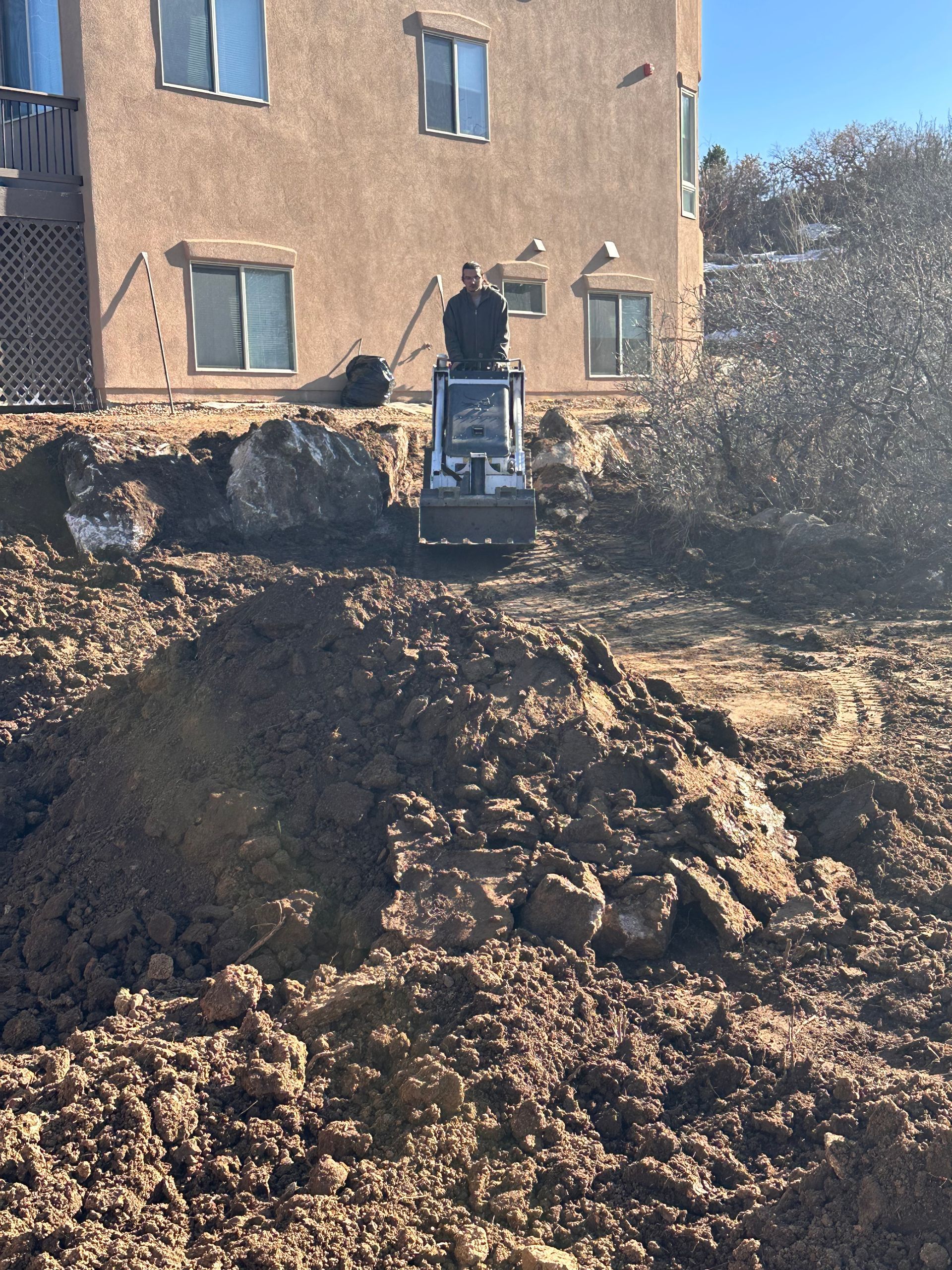 A bulldozer is moving dirt in front of a building