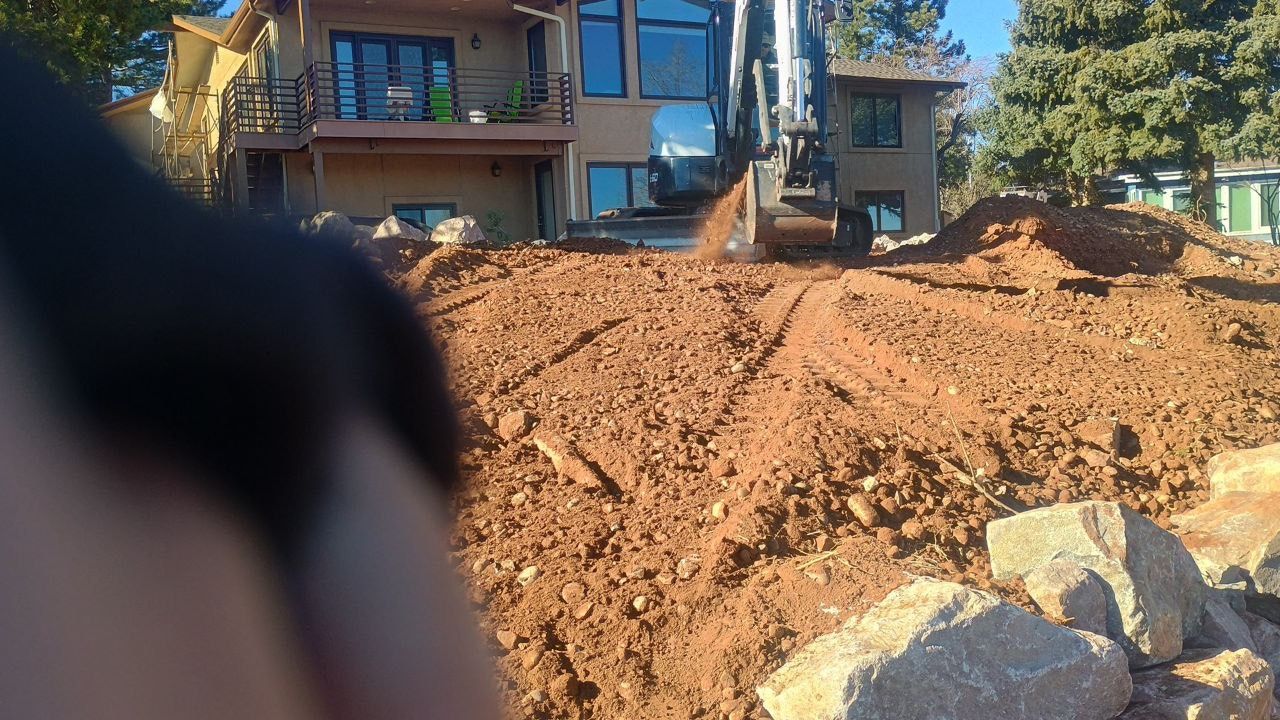 Apartment building behind a large dirt pile at a construction site, with a blurred object in the foreground.