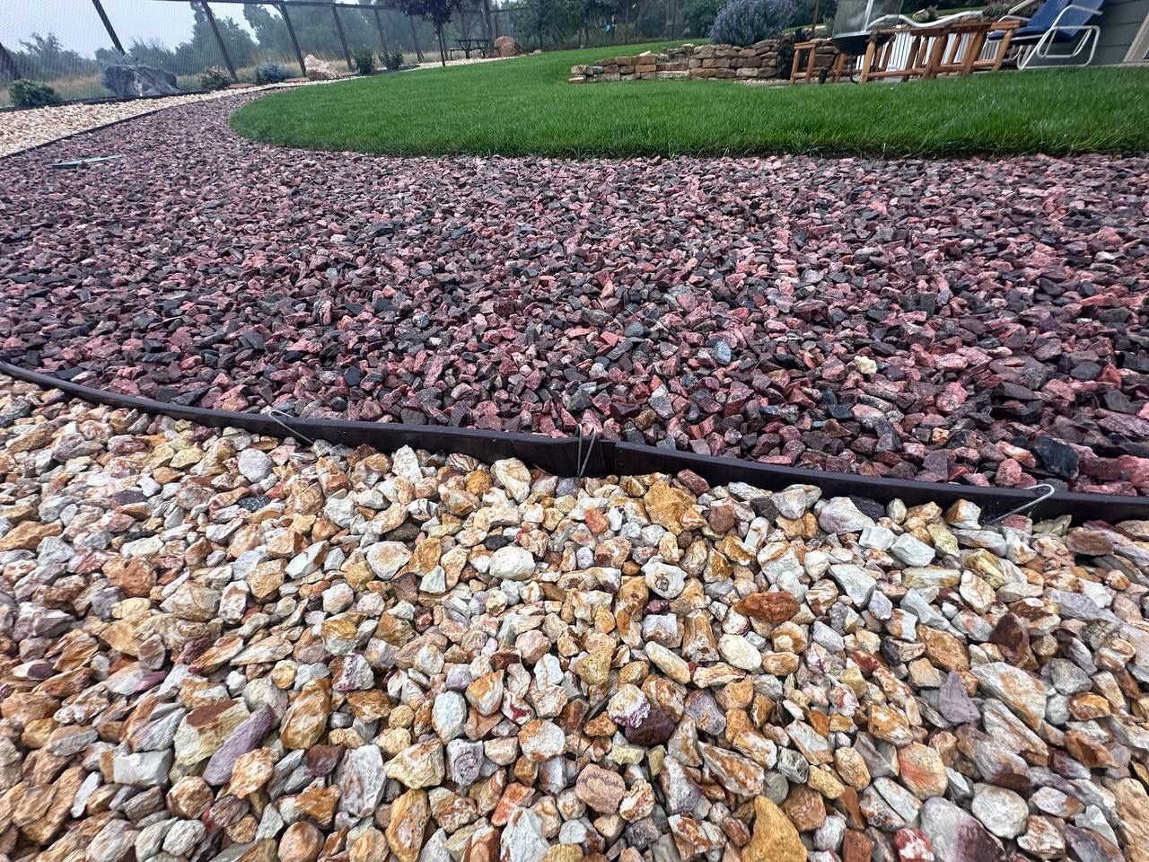 Curved landscaped path with red and beige rocks beside a grassy garden edge