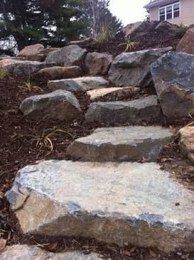 Rocky stone steps leading up a landscaped hillside near a house