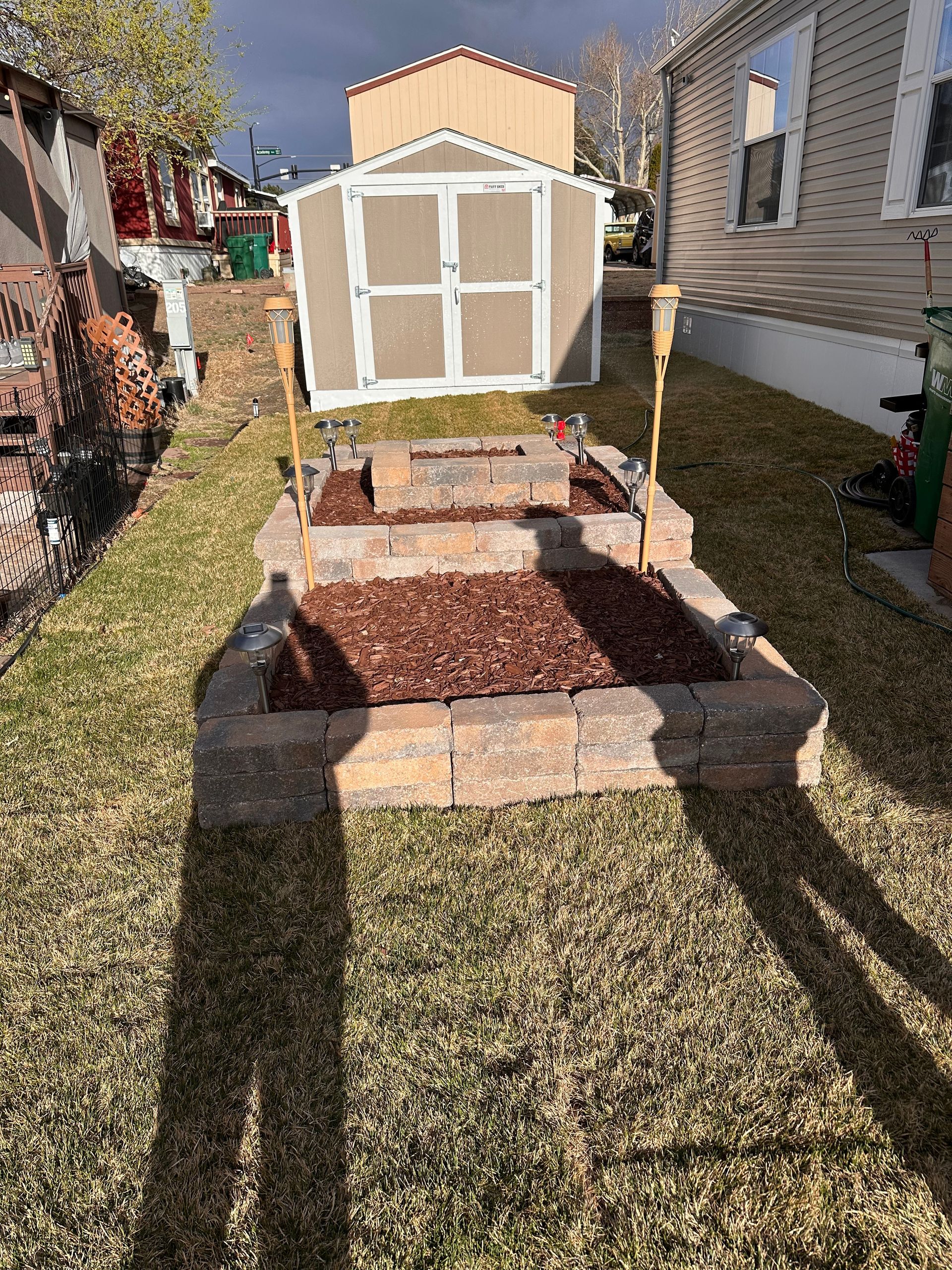 Backyard stone steps leading to a small white garden shed between two houses