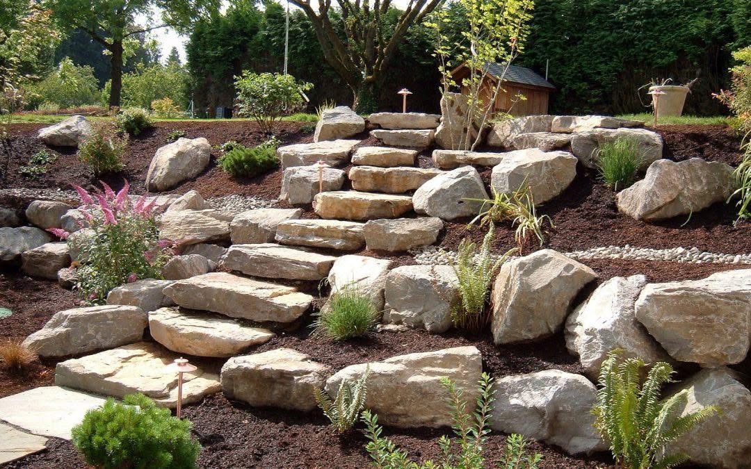 Stone garden steps built into a rocky landscaped slope with greenery and flowers