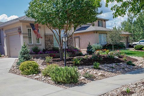 Suburban house with landscaped front yard, driveway, and American flag by the entrance