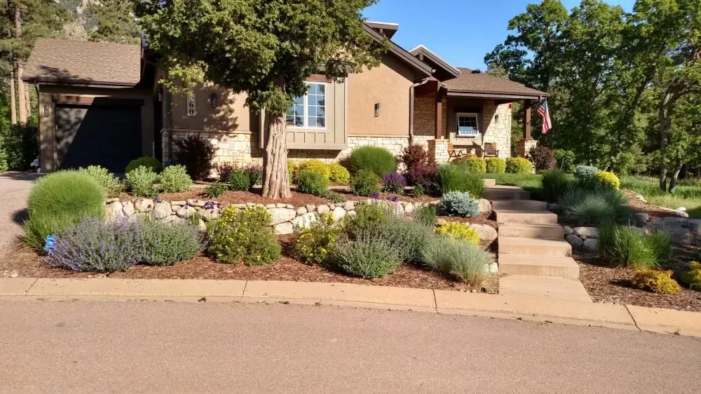 Landscaped suburban home with stone walkway, shrubs, flowers, and trees in front yard