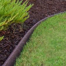 Curved landscape edging separating green grass from dark mulch with a shrub