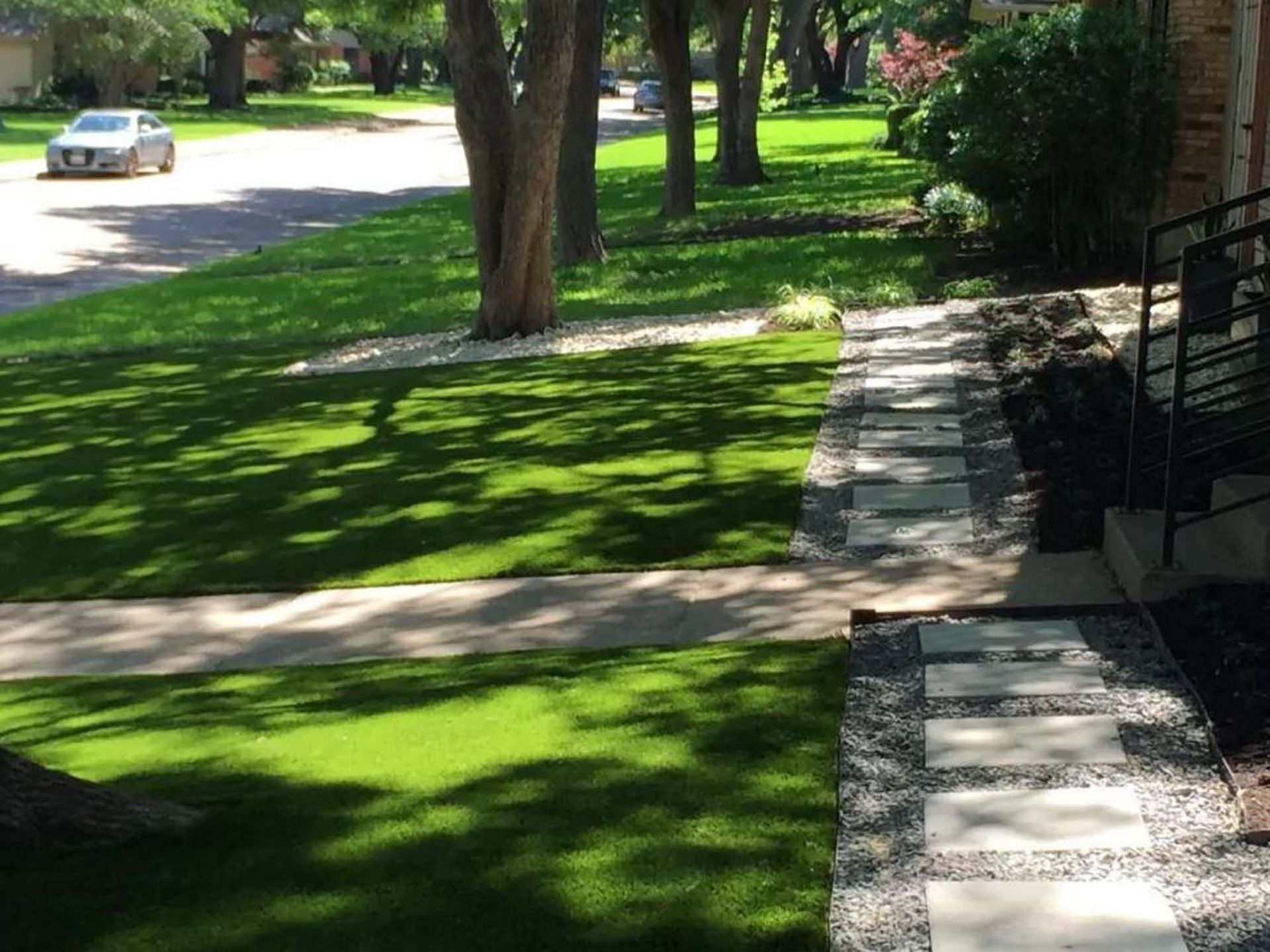 A car is parked on the side of the road next to a lush green lawn