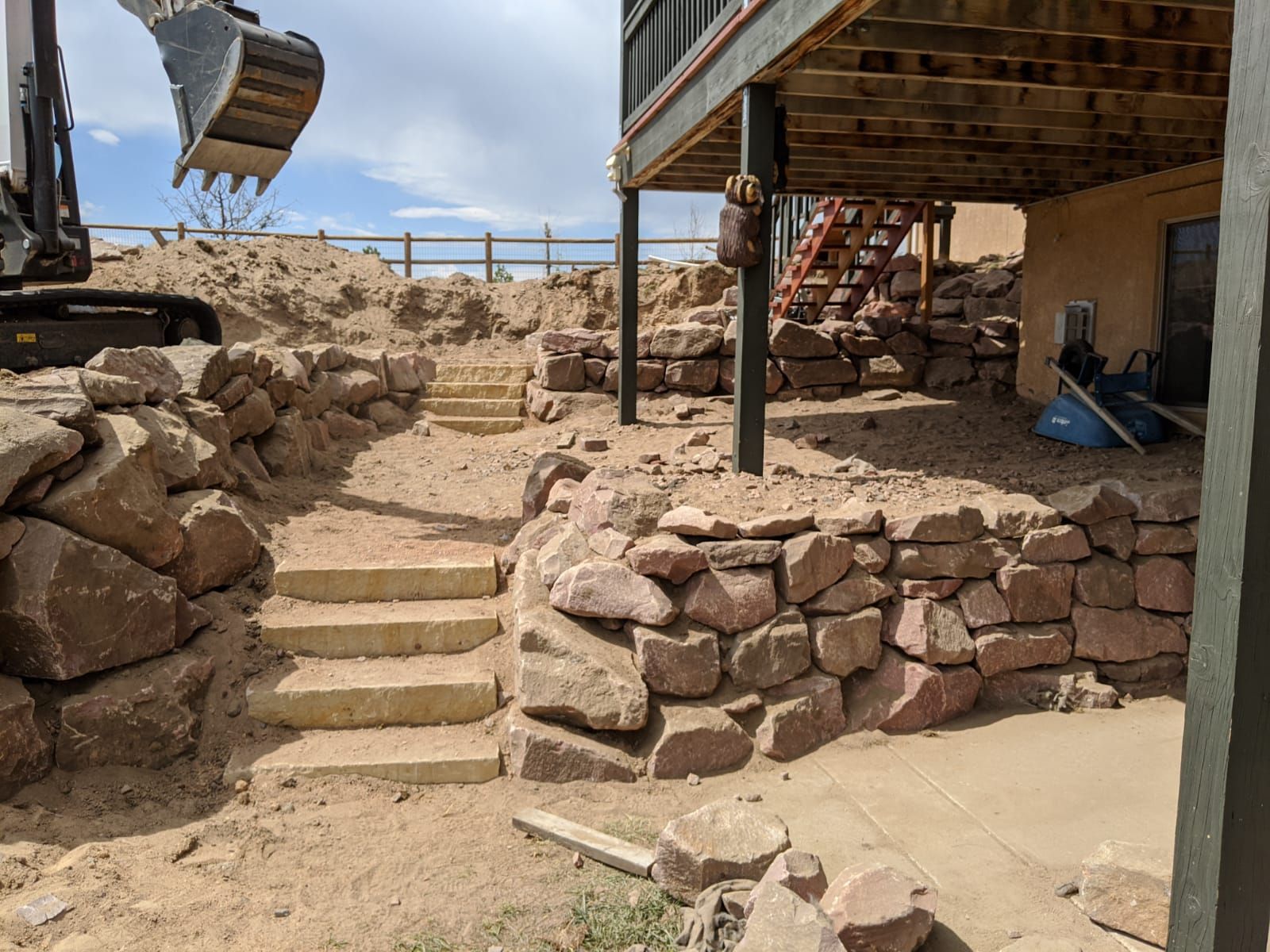 A large rock wall is being built in front of a house