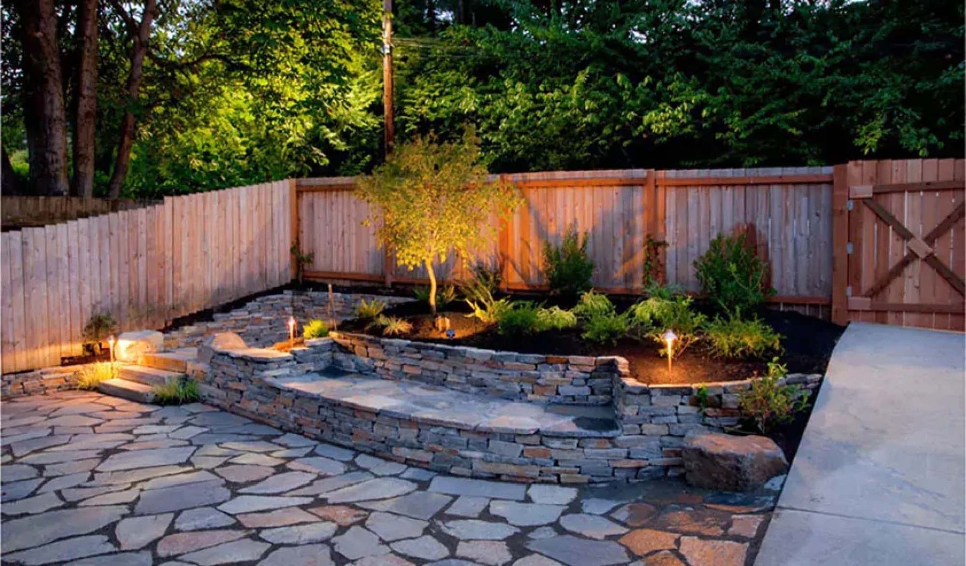 A backyard with a wooden fence and a stone walkway