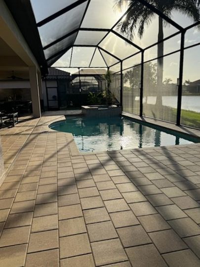 A screened in swimming pool with a palm tree in the background