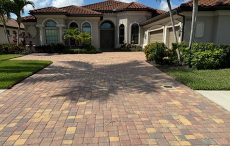 A large house with a brick driveway in front of it.