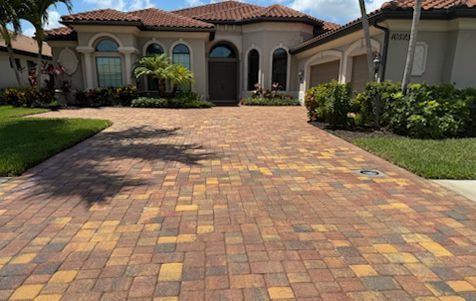 A large house with a brick driveway in front of it.