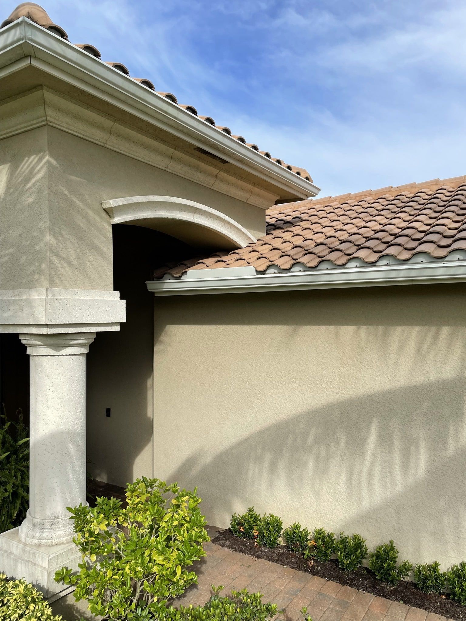 A house with a tiled roof and a pillar in front of it