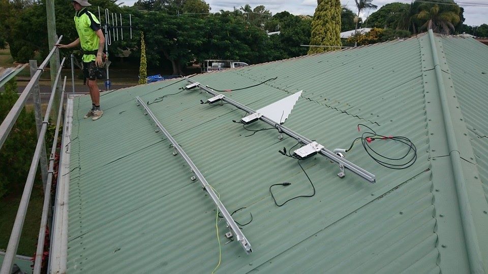A Person on A Rooftop Installing Solar Panels — Kaplan Roofing in Walkervale, QLD