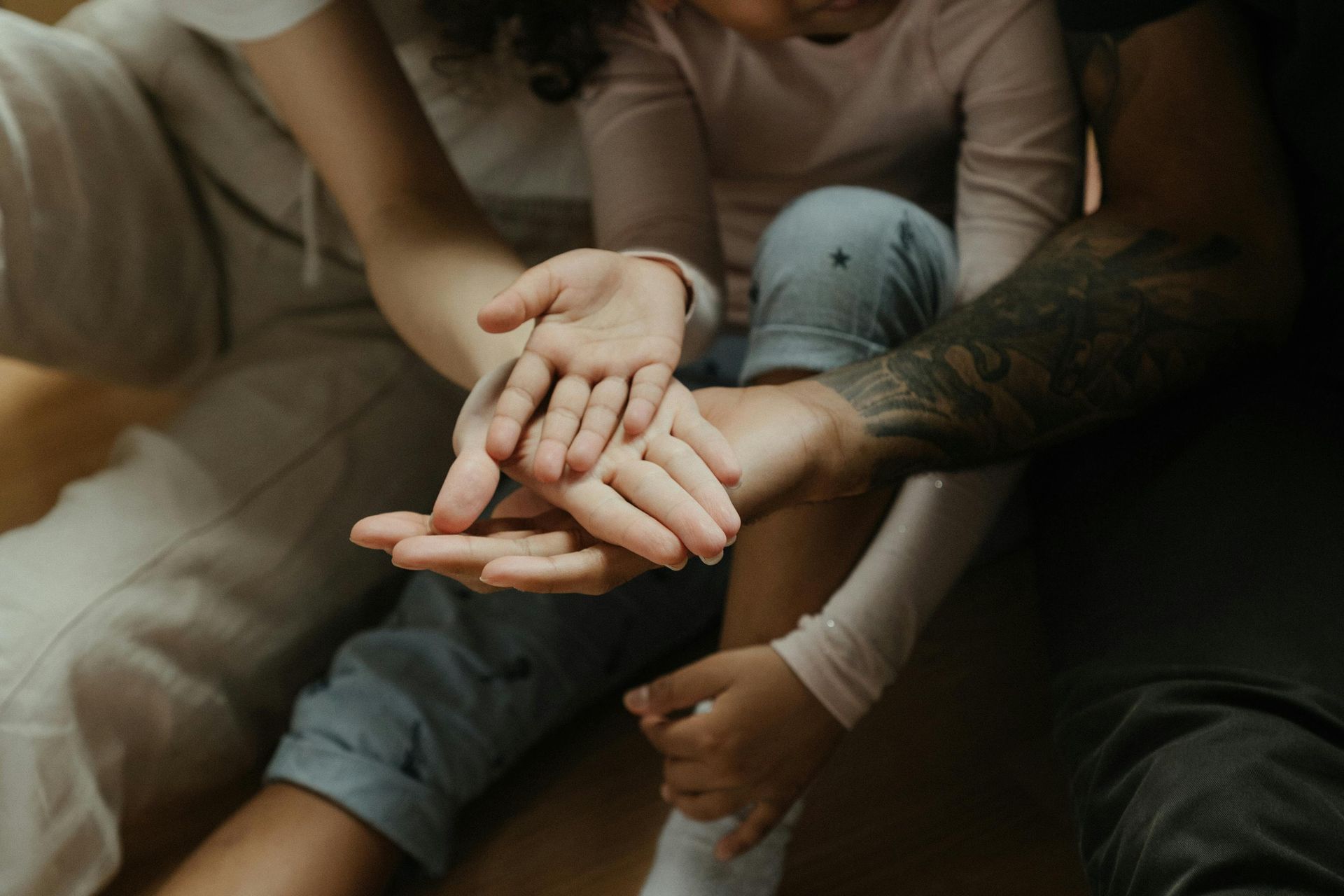 A family is sitting on the floor holding hands.
