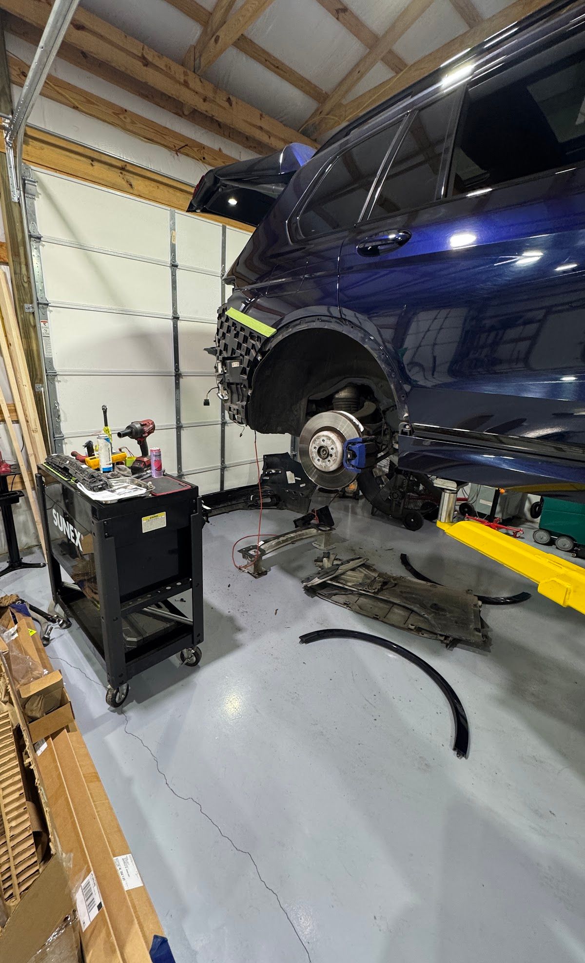 Blue SUV lifted in a garage with front wheel removed, exposing the brake assembly | KB Motor Works