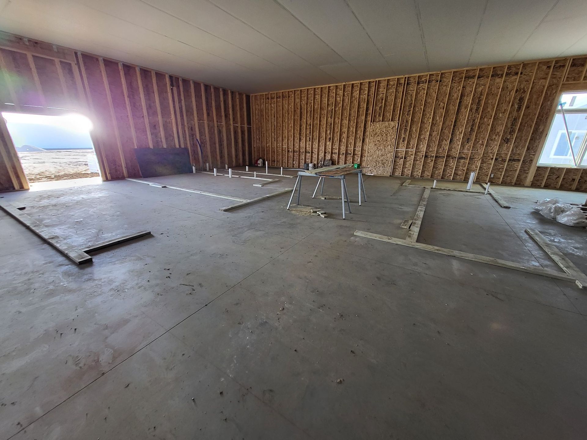 Unfinished room with exposed wood framing, concrete floor, and scattered construction materials