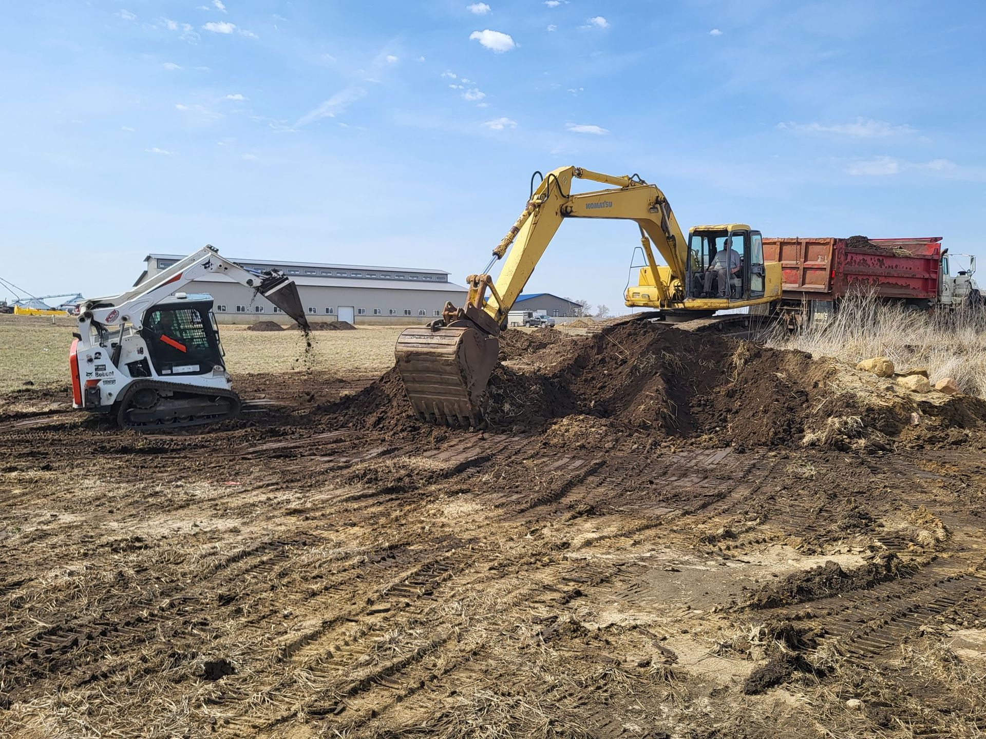 Yellow excavator digging dirt beside a small white car at a muddy construction site
