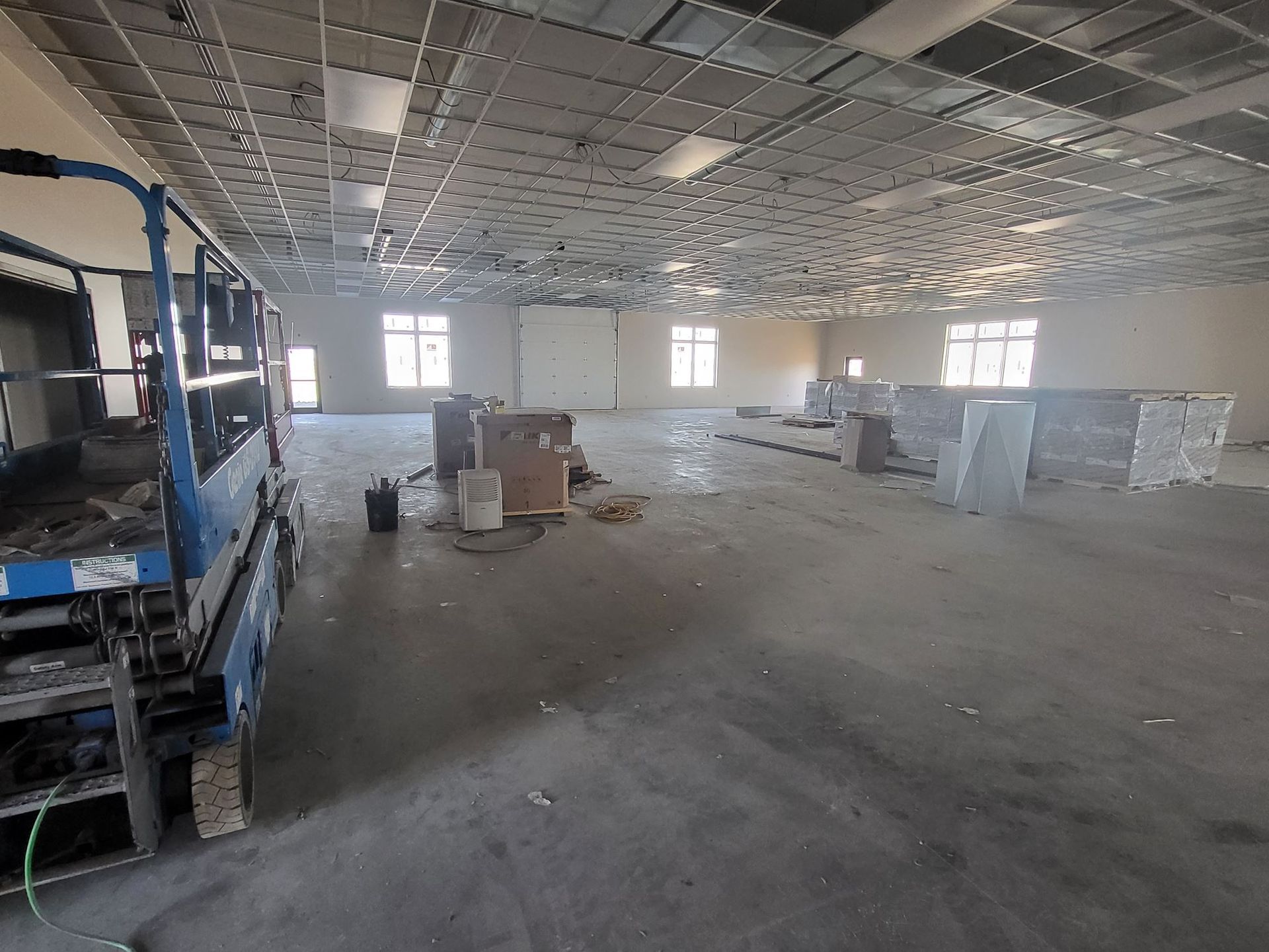 Empty warehouse interior with blue metal racks and stacks of materials on the floor under a high ceiling