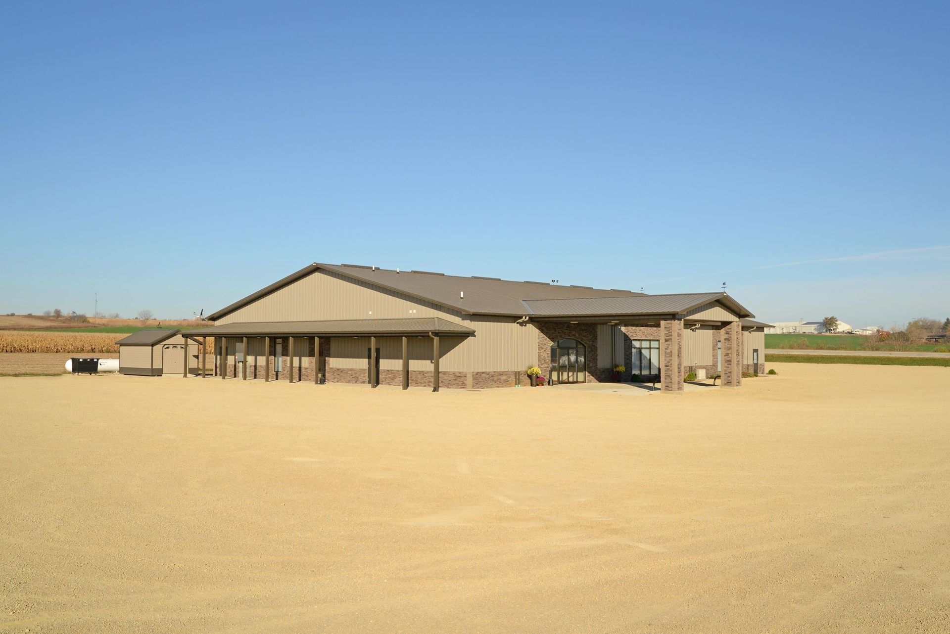 Single-story tan building on a vast dry field under a clear blue sky
