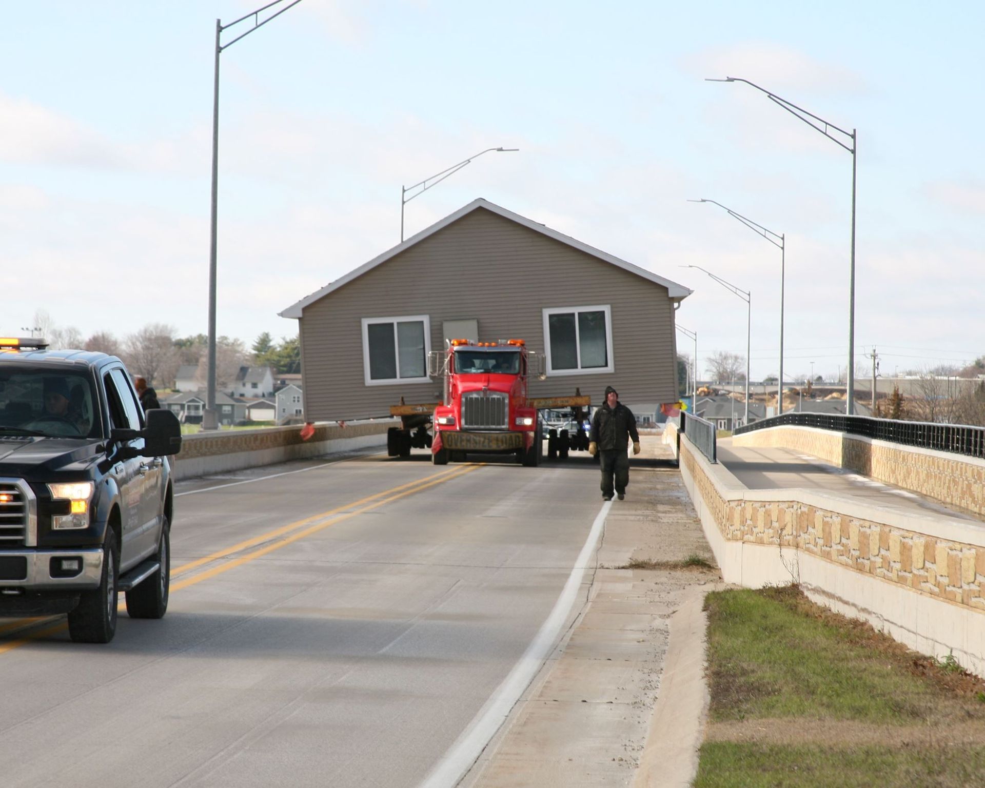Red fire truck on a bridge with two people nearby and a black SUV approaching on the left.